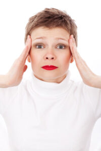 Woman with hands on head looking stressed or as if she has a headache